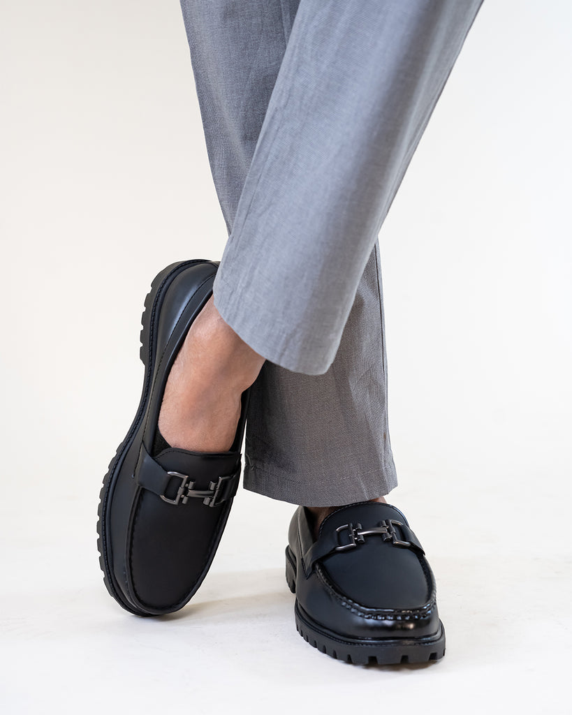 A man wearing black loafers and gray pants.