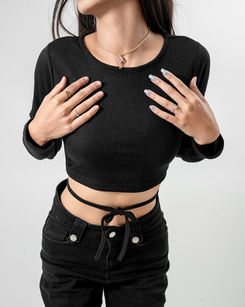 A woman wearing a black crop top and black jeans