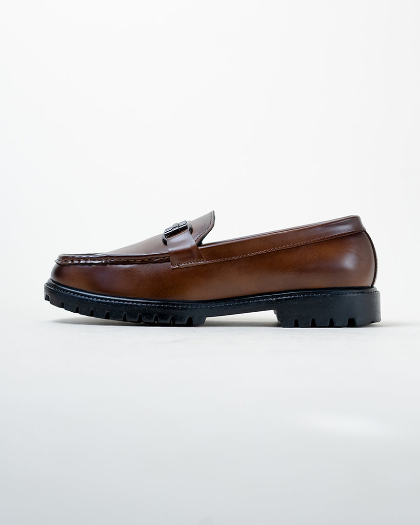 A pair of brown loafers on a white surface.