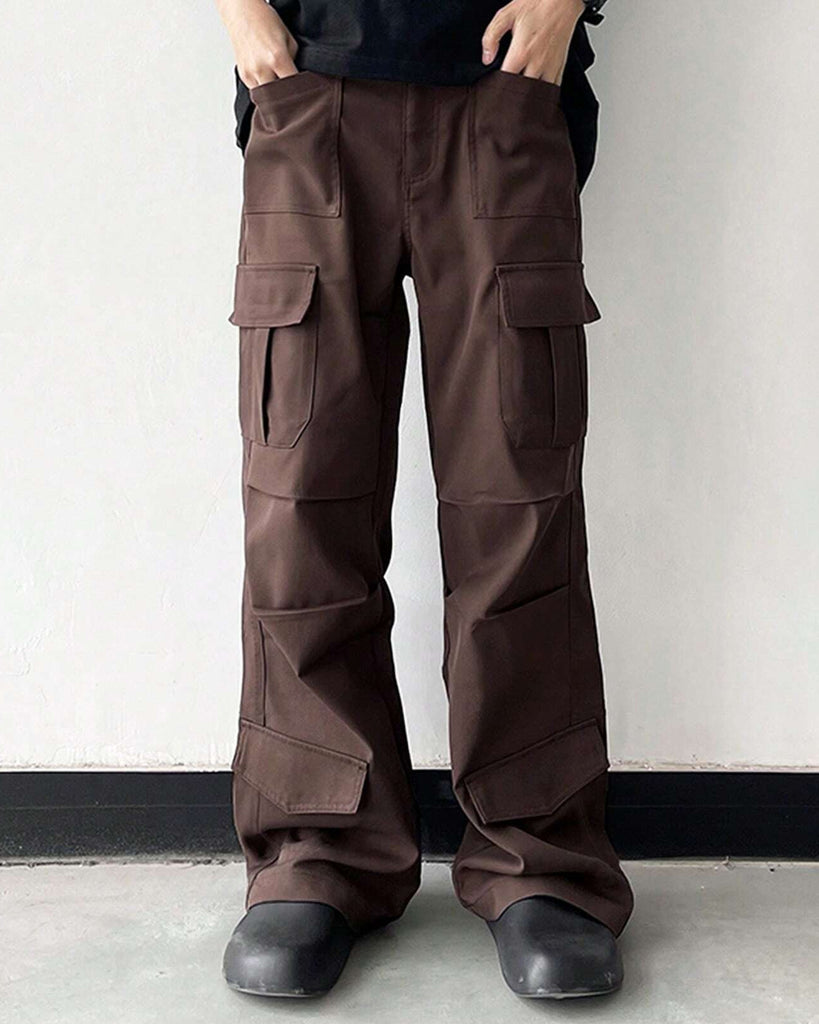 A man wearing brown cargo pants standing against a wall.