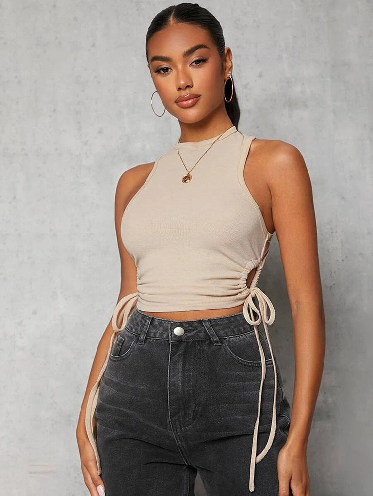 The model is wearing a beige crop top and black jeans.